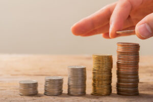 A person placing coins in stacks that get taller from left to right.